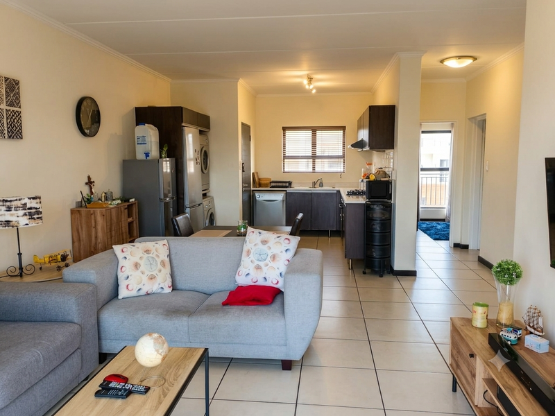 Open-plan living and kitchen area featuring tiled flooring, dark cabinetry, and a functional layout connecting to a balcony.
