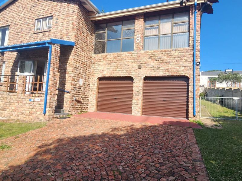 Front elevation of a double-storey face brick house featuring a paved driveway and a double garage with roller shutter doors.