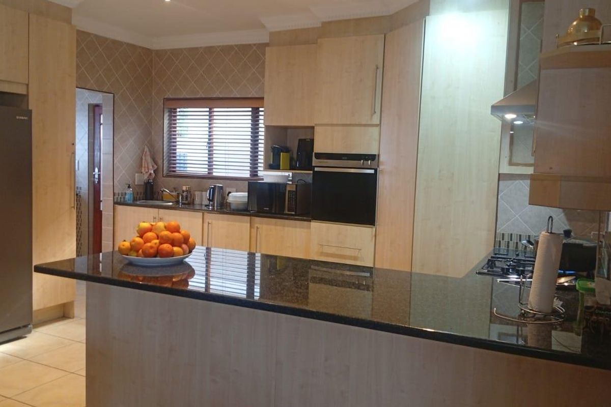 A functional kitchen featuring light wood cabinetry, dark granite countertops, a built-in oven, gas hob, and tiled flooring.