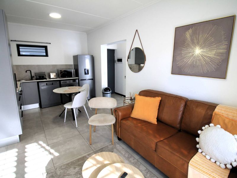 A modern open-plan living and kitchen area featuring tiled flooring, contemporary cabinetry, and a functional layout suitable for compact apartment living.