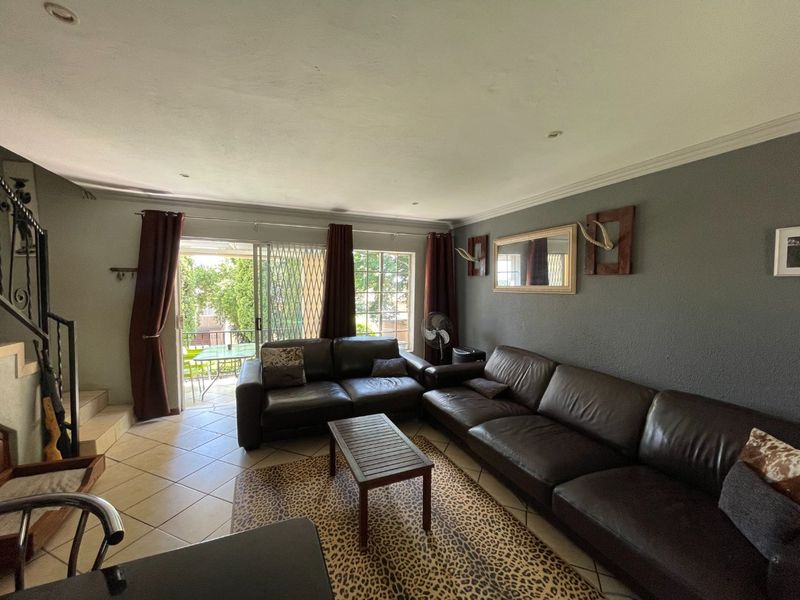 Spacious living room featuring tiled flooring, recessed lighting, and a sliding glass door providing access to an outdoor patio area.