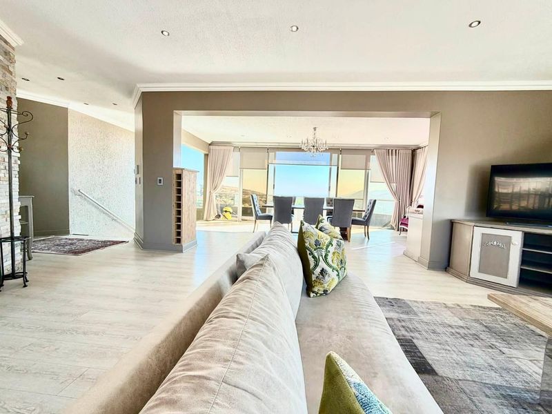 Spacious open-plan living and dining area featuring light laminate flooring, recessed lighting, and large sliding doors leading to a scenic outdoor view.