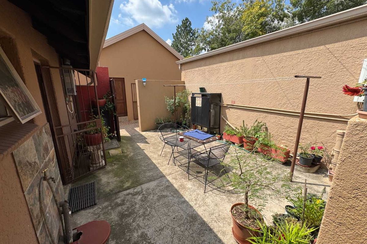 A private rear courtyard featuring concrete paving, a built-in braai, and security access, offering a functional outdoor space for relaxation and entertaining.