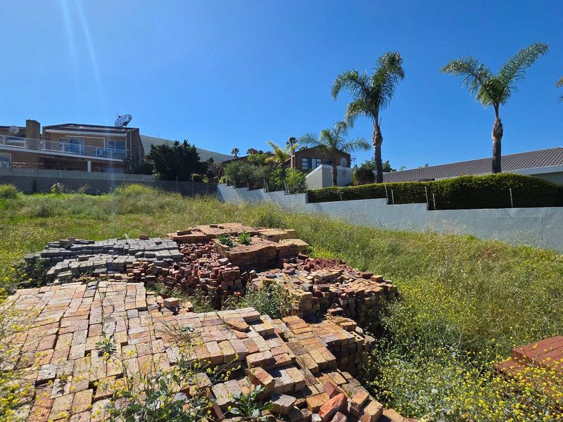 Vacant residential land featuring a perimeter wall and scattered building materials, situated in an established neighborhood.