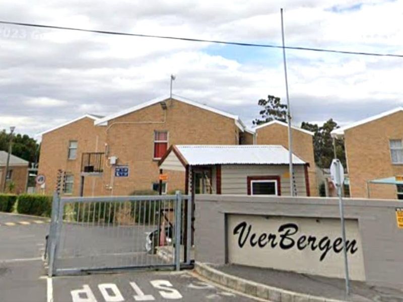 Front entrance view of the Vierbergen residential complex, featuring a security gate, guard booth, and brick building facades.