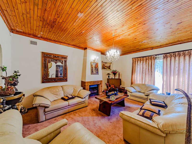 Spacious living room featuring a distinctive timber tongue and groove ceiling, a central brick fireplace, and direct access to the outdoors via sliding glass doors.