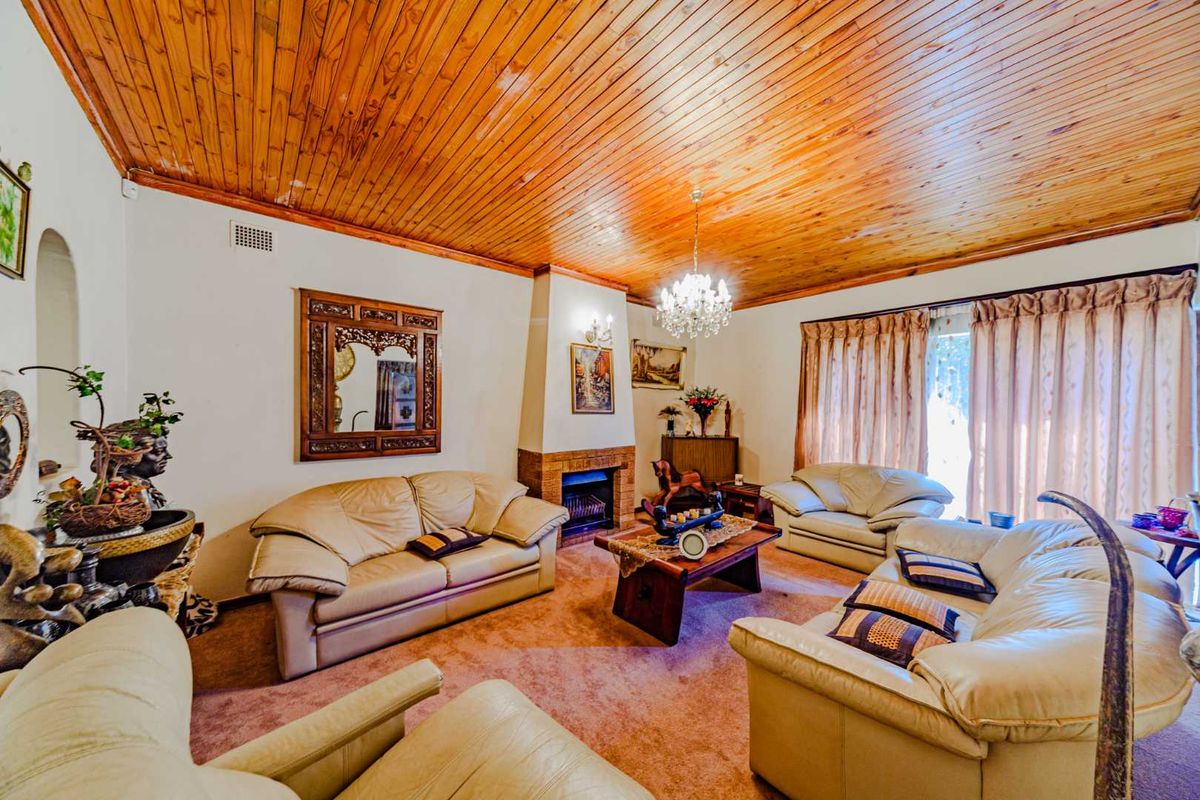 Spacious living room featuring a distinctive timber tongue and groove ceiling, a central brick fireplace, and direct access to the outdoors via sliding glass doors.