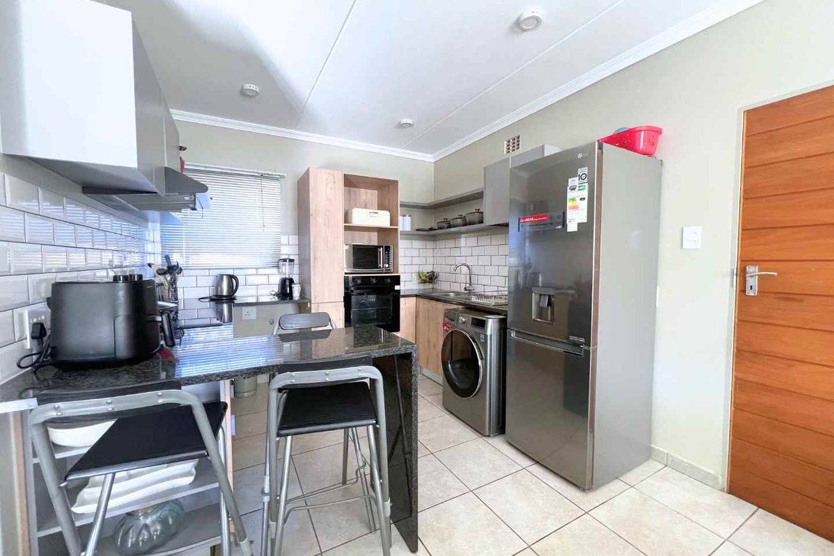 A functional kitchen featuring light wood cabinetry, subway tile backsplash, granite countertops, and integrated appliances including an oven and hob.