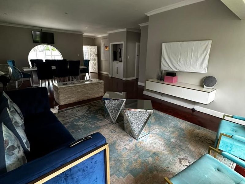 Spacious open-plan living and dining area featuring hardwood flooring, recessed lighting, and a neutral color palette with a distinct architectural archway.