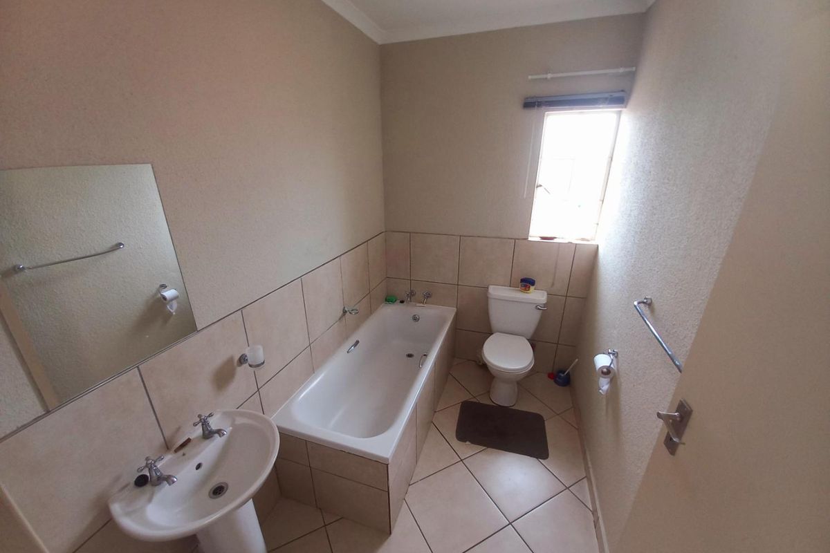 A functional bathroom featuring a pedestal basin, a built-in bathtub with tiled surround, and a standard toilet.