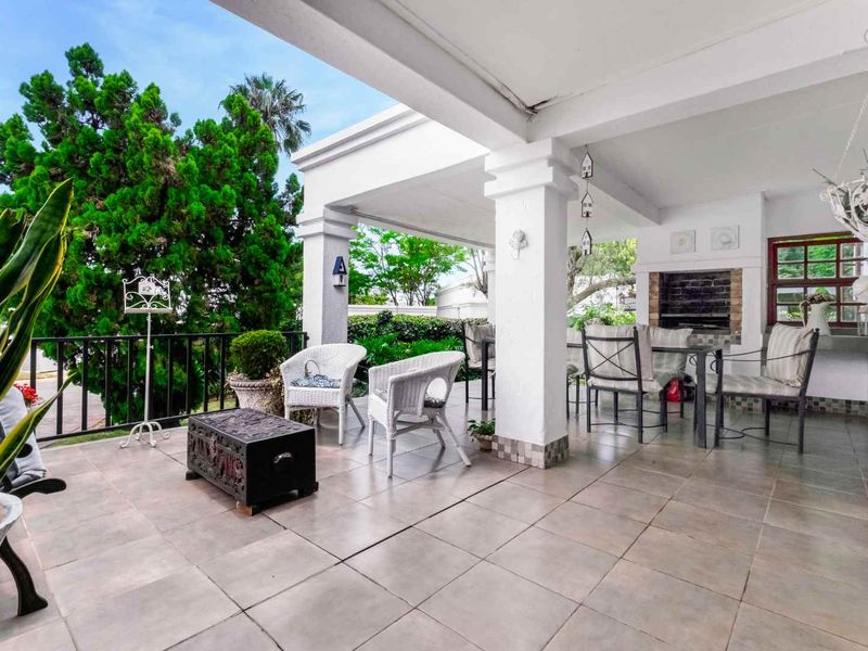 Spacious covered patio featuring tiled flooring and a built-in braai, ideal for outdoor entertaining and relaxation.