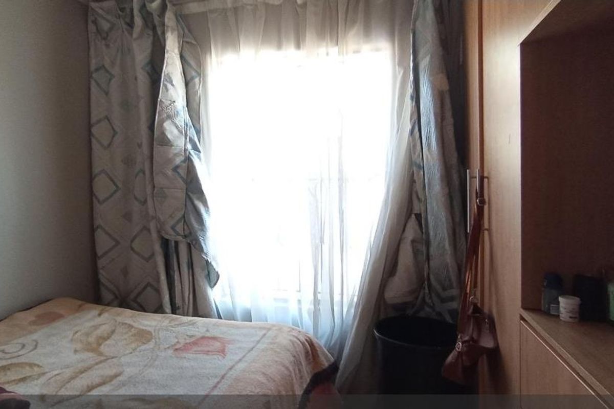 A bedroom featuring built-in wooden cabinetry and a window with curtains.