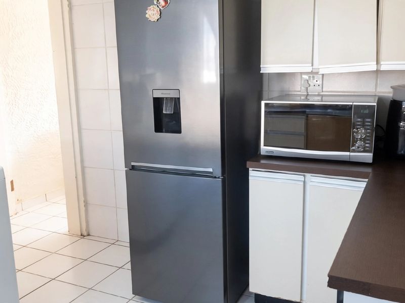 A functional kitchen area featuring tiled walls and flooring, built-in cabinetry, and a dark laminate countertop.