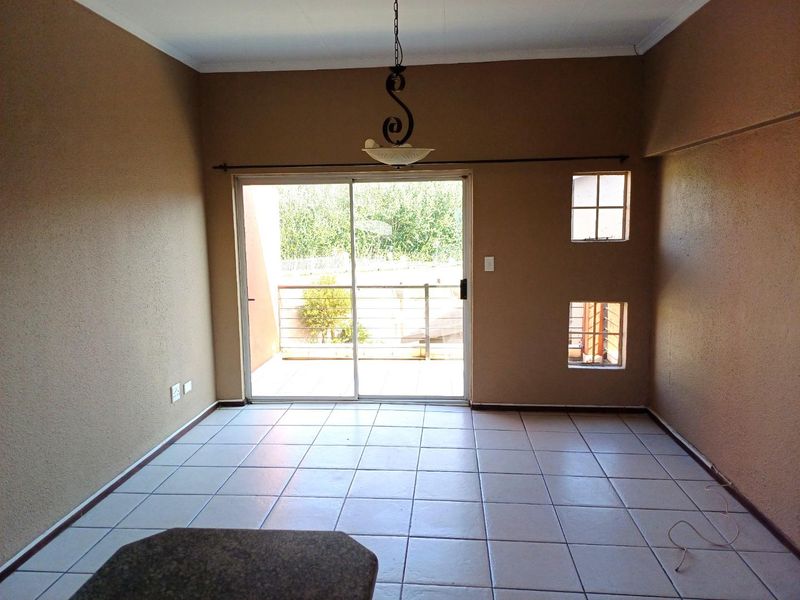 An empty living area featuring tiled flooring, a sliding glass door leading to a balcony, and neutral wall finishes.