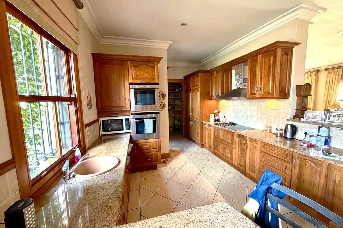 Spacious kitchen featuring traditional wooden cabinetry, granite countertops, built-in double oven, and a separate pantry area with tiled flooring.