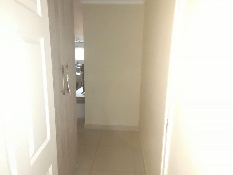 A functional hallway featuring tiled flooring and a built-in cupboard, providing access to the rest of the apartment.
