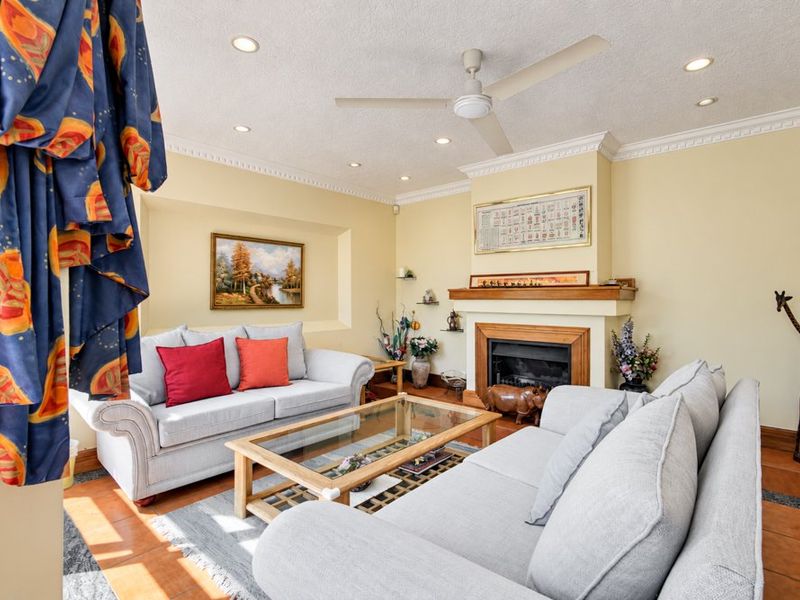 A comfortable living room featuring a fireplace with a wooden mantelpiece, recessed wall niche, crown molding, and tiled flooring.