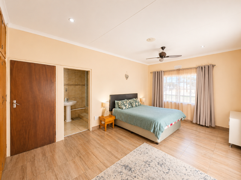 Spacious bedroom featuring tiled flooring, recessed lighting, a ceiling fan, built-in cupboards, and an adjoining en-suite bathroom.
