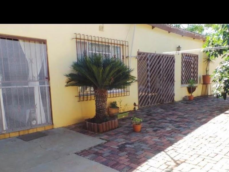 Rear exterior view of the property featuring a paved patio area, security bars on windows, and sliding door access.
