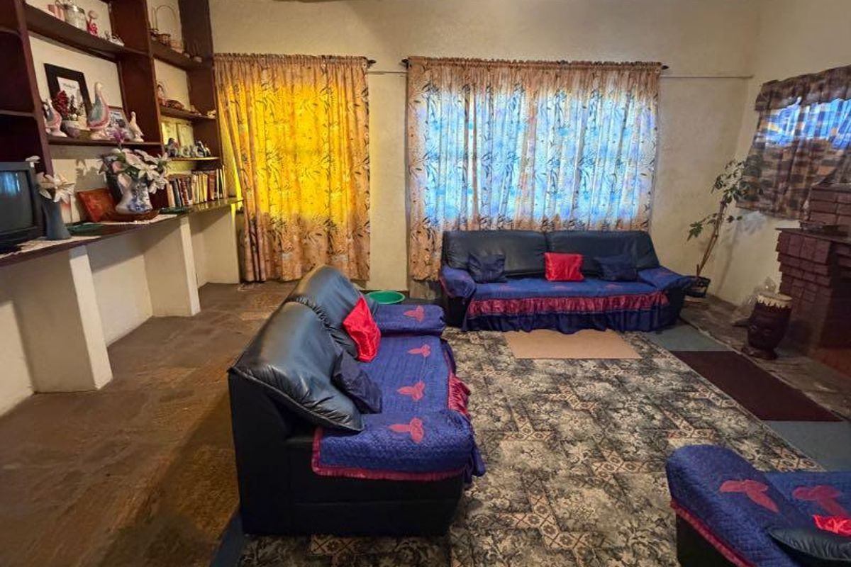 Living room featuring stone flooring, built-in shelving, and a brick fireplace, currently requiring significant ceiling repairs and general refurbishment.