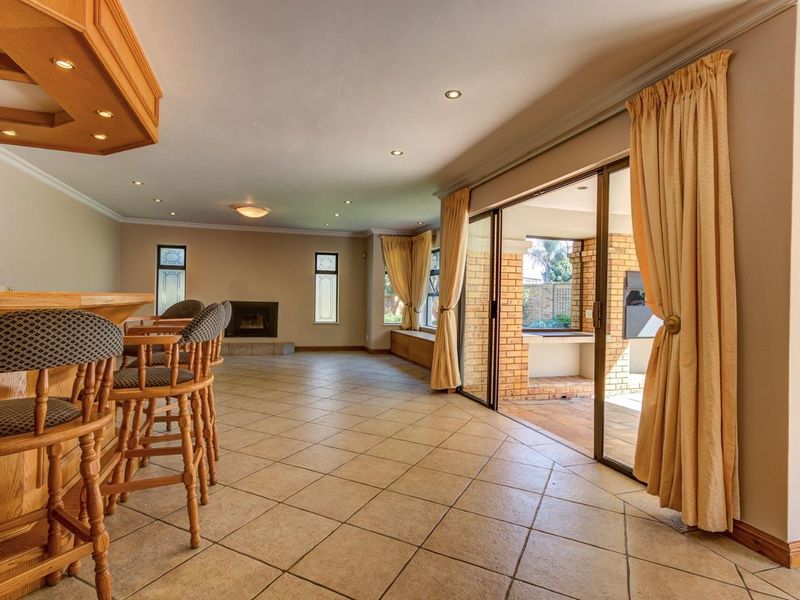 Spacious entertainment area featuring a built-in bar, fireplace, and large sliding glass doors that open onto an outdoor patio space.