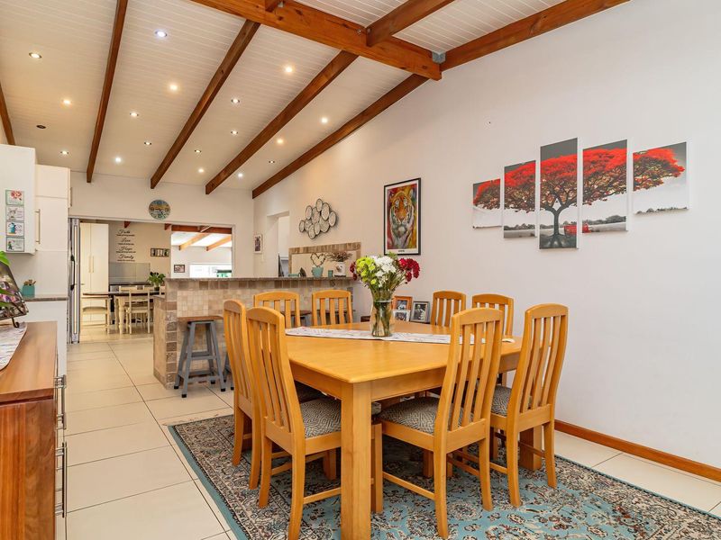Spacious open-plan dining and kitchen area featuring exposed timber ceiling beams, recessed lighting, and tiled flooring throughout.