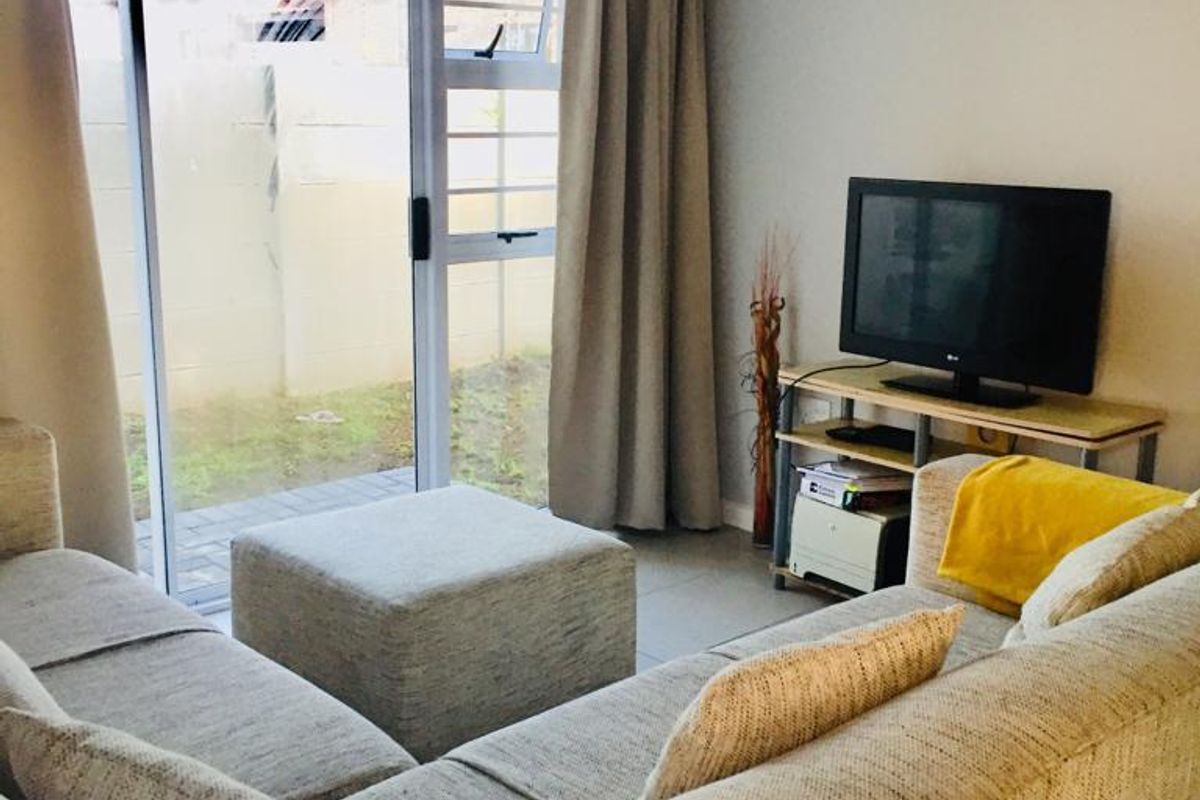 A comfortable living room featuring tiled flooring and large sliding glass doors that provide direct access to the outdoor patio area.
