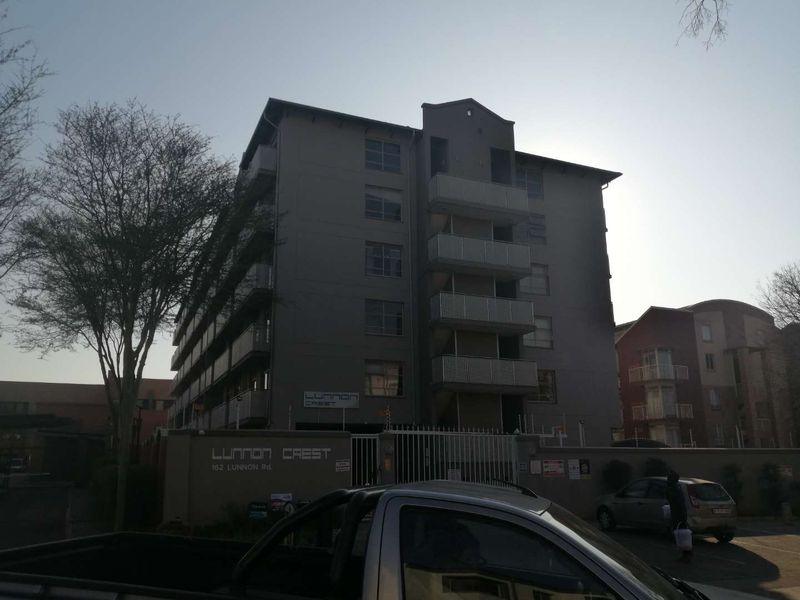 Exterior view of the Lunnon Crest apartment complex, featuring multi-story residential units with balconies, secure perimeter walling, and gated access.