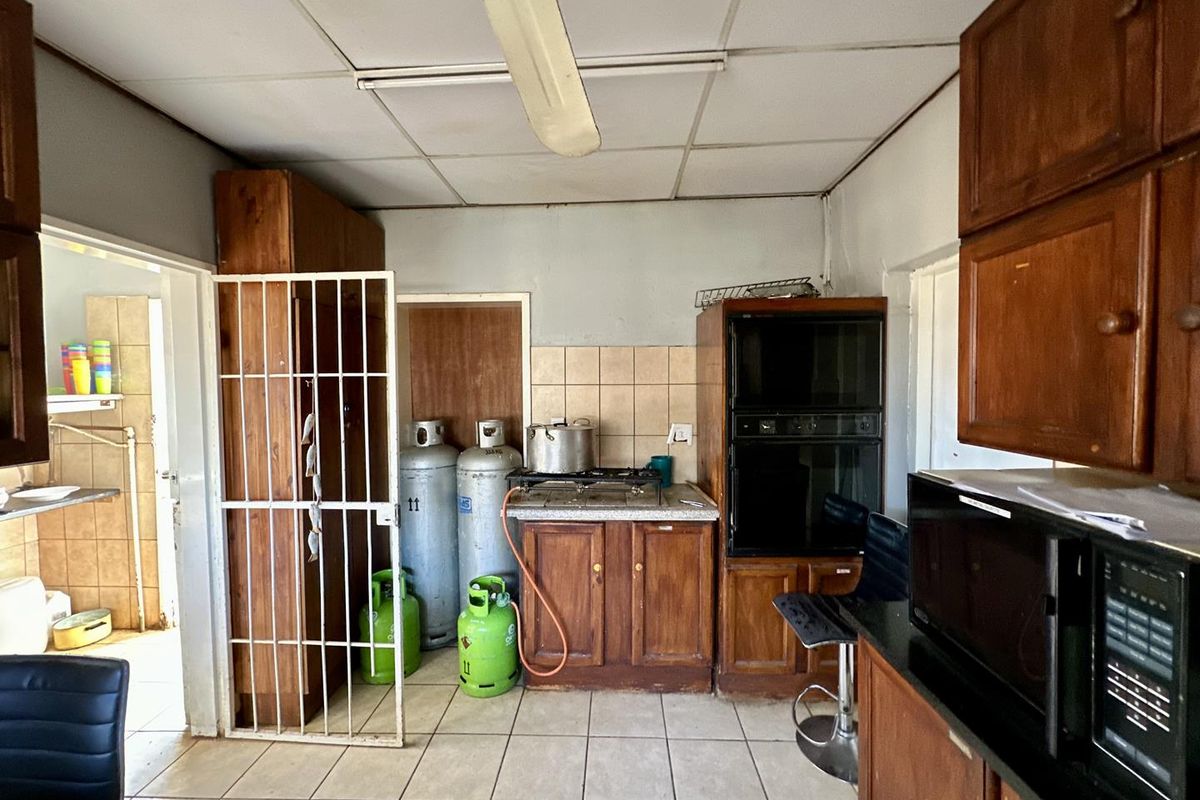 A dated kitchen featuring wooden cabinetry, tiled flooring, and built-in oven, requiring modernization to improve functionality and aesthetic appeal.