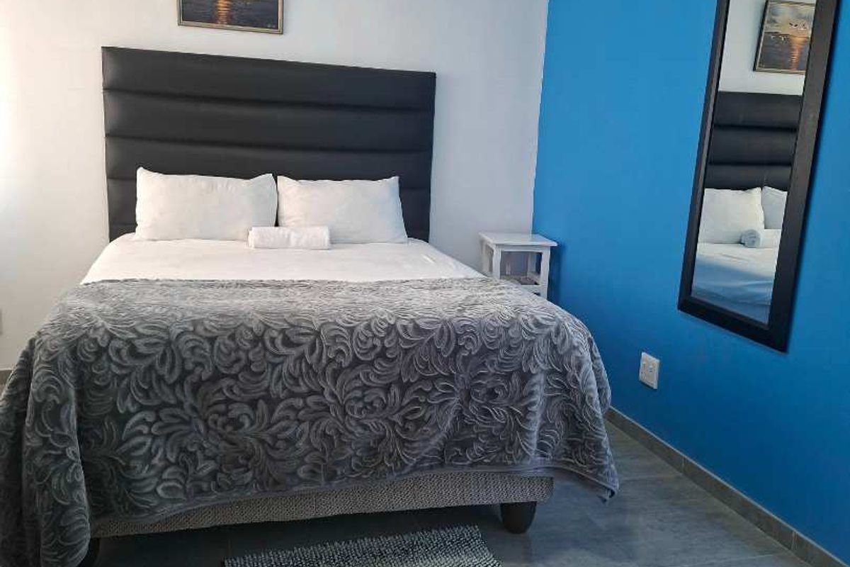 A bedroom featuring tiled flooring and a bold blue accent wall, providing a clean and functional sleeping space.