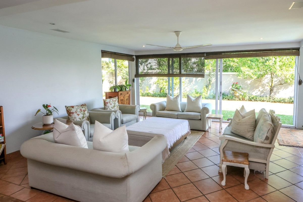 Spacious living room featuring terracotta floor tiles, a ceiling fan, and large sliding glass doors providing direct access to the garden.