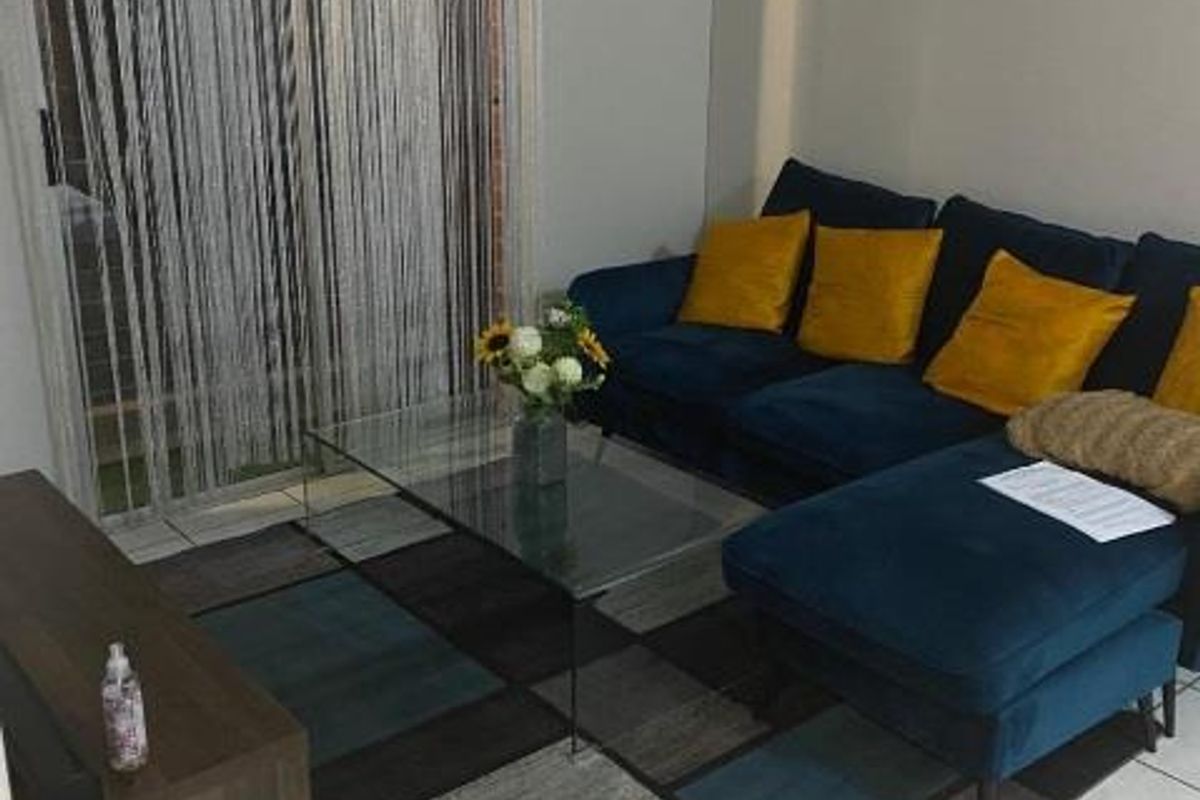 A living room area featuring tiled flooring and a sliding glass door providing access to the exterior.