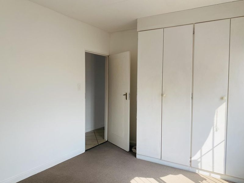 An empty bedroom featuring neutral walls, carpeted flooring, and built-in cupboards, offering a blank canvas for personalization.