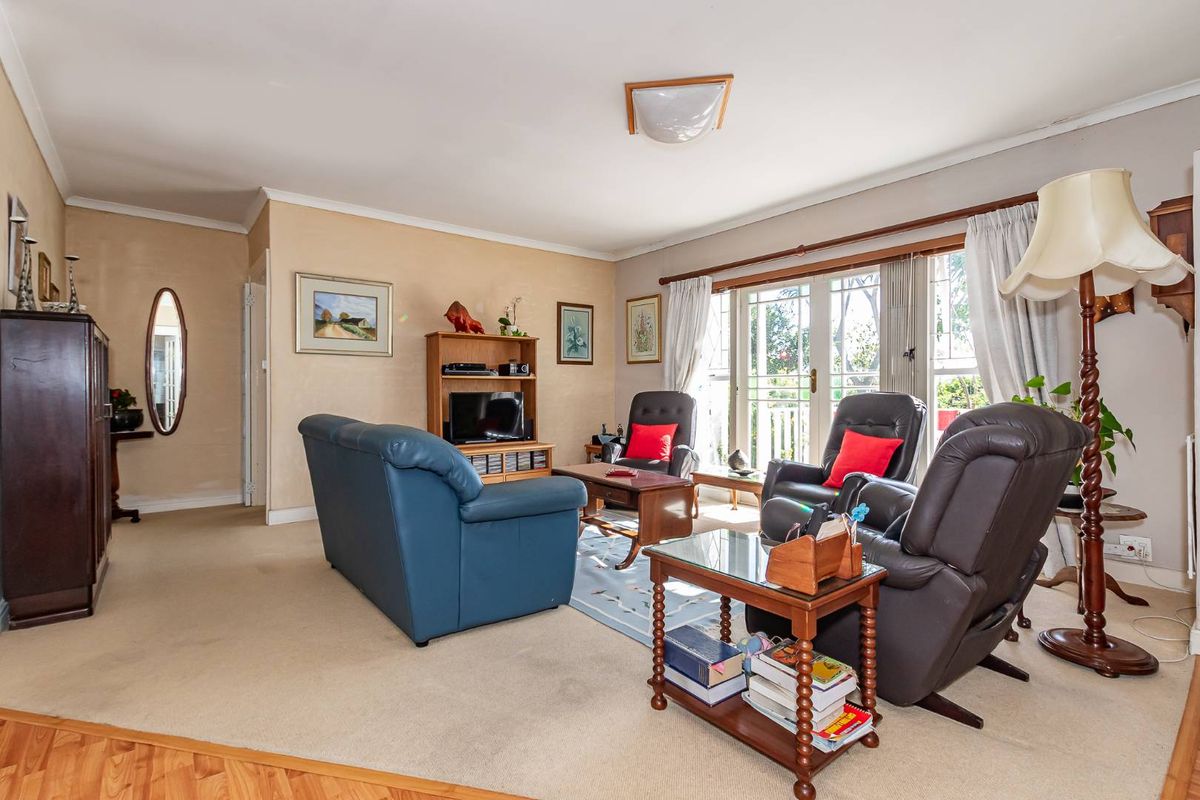 A spacious living room featuring neutral carpeting, large glass sliding doors providing natural light, and access to an outdoor area.