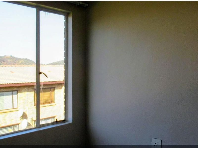 An empty bedroom featuring a large window with views of the surrounding residential complex.