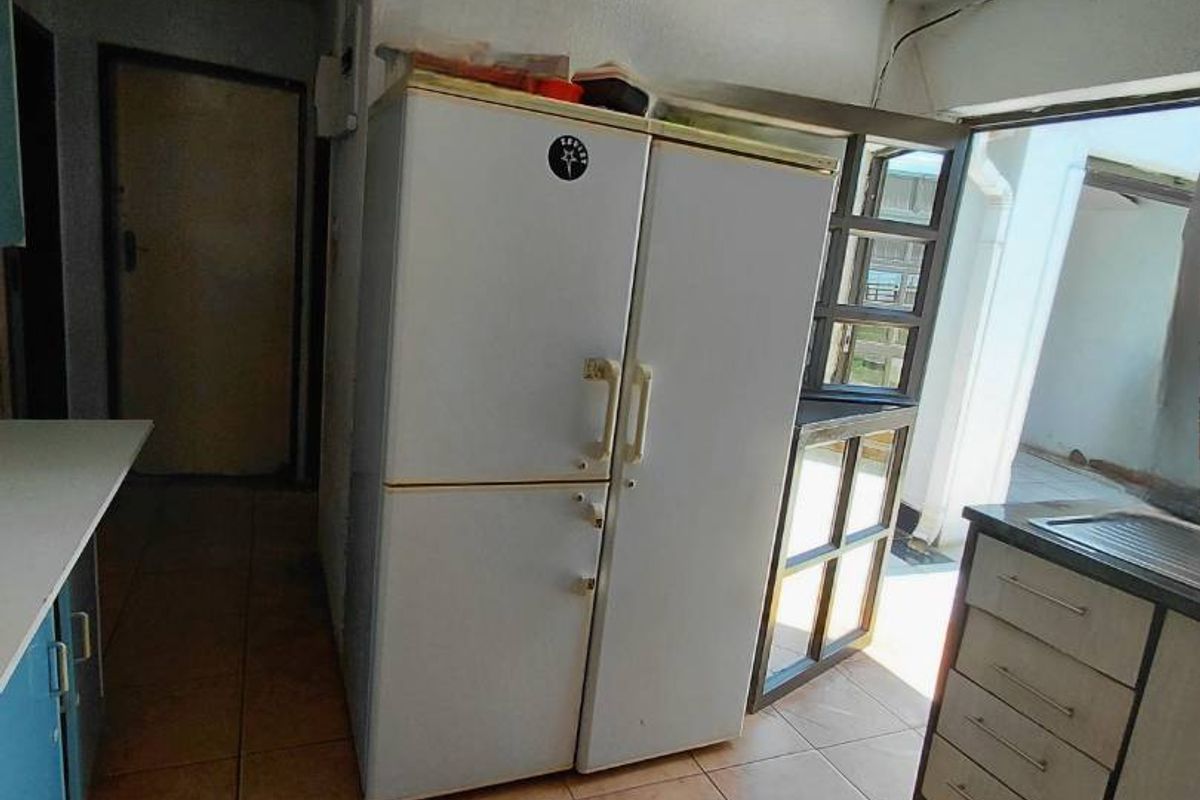 A dated kitchen featuring tiled flooring, built-in cabinetry, and a sink, requiring modernization to improve functionality and aesthetic appeal.