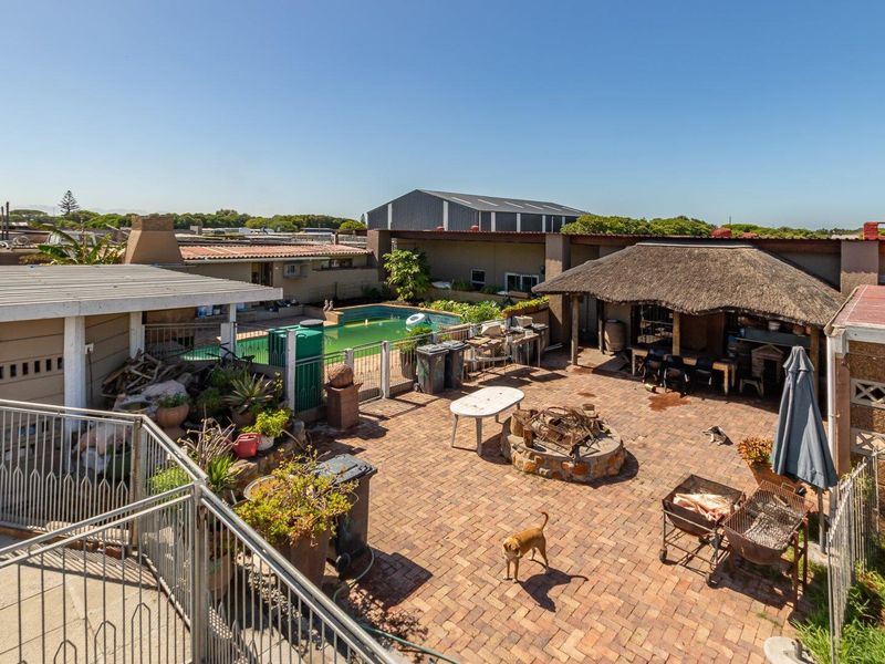 Outdoor entertainment area featuring a swimming pool, thatched lapa, stone fire pit, and brick paved patio space.