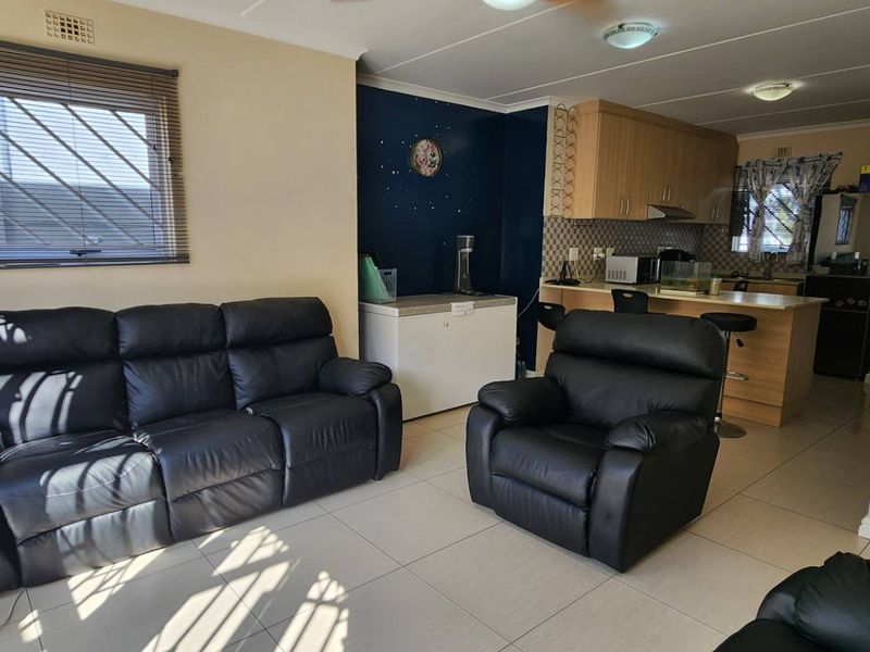 Open-plan living area featuring tiled flooring and a functional kitchen with breakfast bar, cabinetry, and integrated extractor fan.