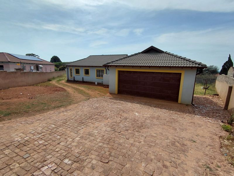 Front exterior view of the house featuring a cobblestone driveway, a single garage, and a perimeter wall.