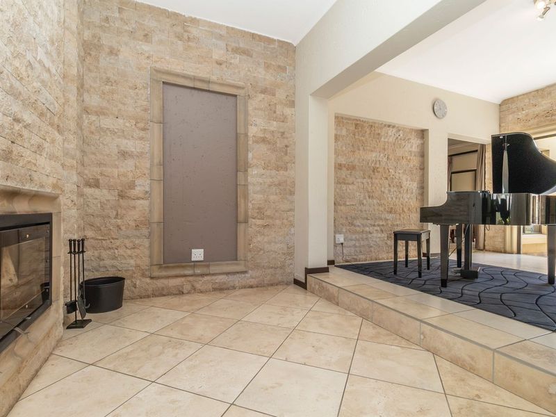 Spacious living area featuring elegant stone-clad walls, a built-in fireplace, and a raised platform area with tiled flooring throughout.