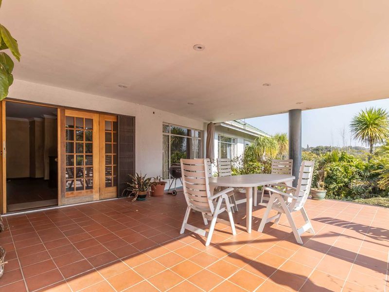 A spacious covered patio featuring terracotta tiled flooring, recessed lighting, and timber sliding doors providing seamless access to the interior living space.