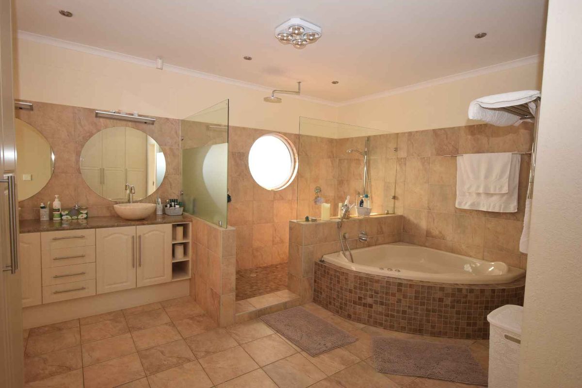 Spacious bathroom featuring a corner jetted tub, walk-in shower with glass enclosure, dual vanity with vessel sinks, and neutral tile finishes.