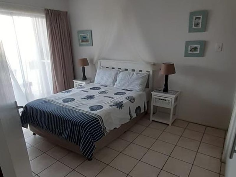 A functional bedroom featuring tiled flooring and a sliding glass door providing access to the exterior.