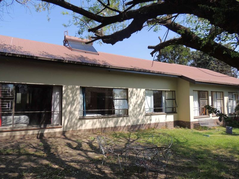 Rear view of the house featuring a metal roof, solar water heater, and large windows overlooking a garden area.