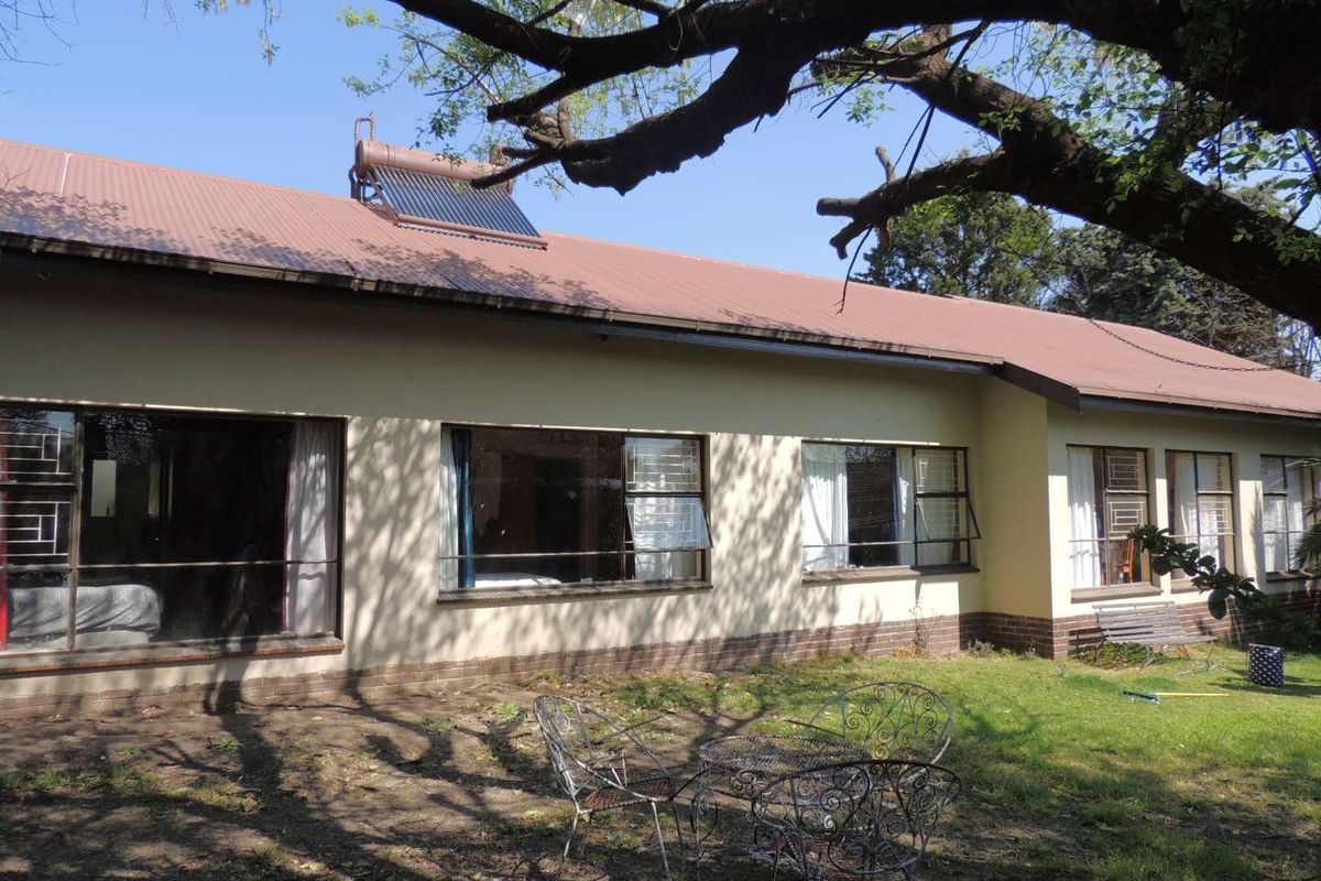 Rear view of the house featuring a metal roof, solar water heater, and large windows overlooking a garden area.