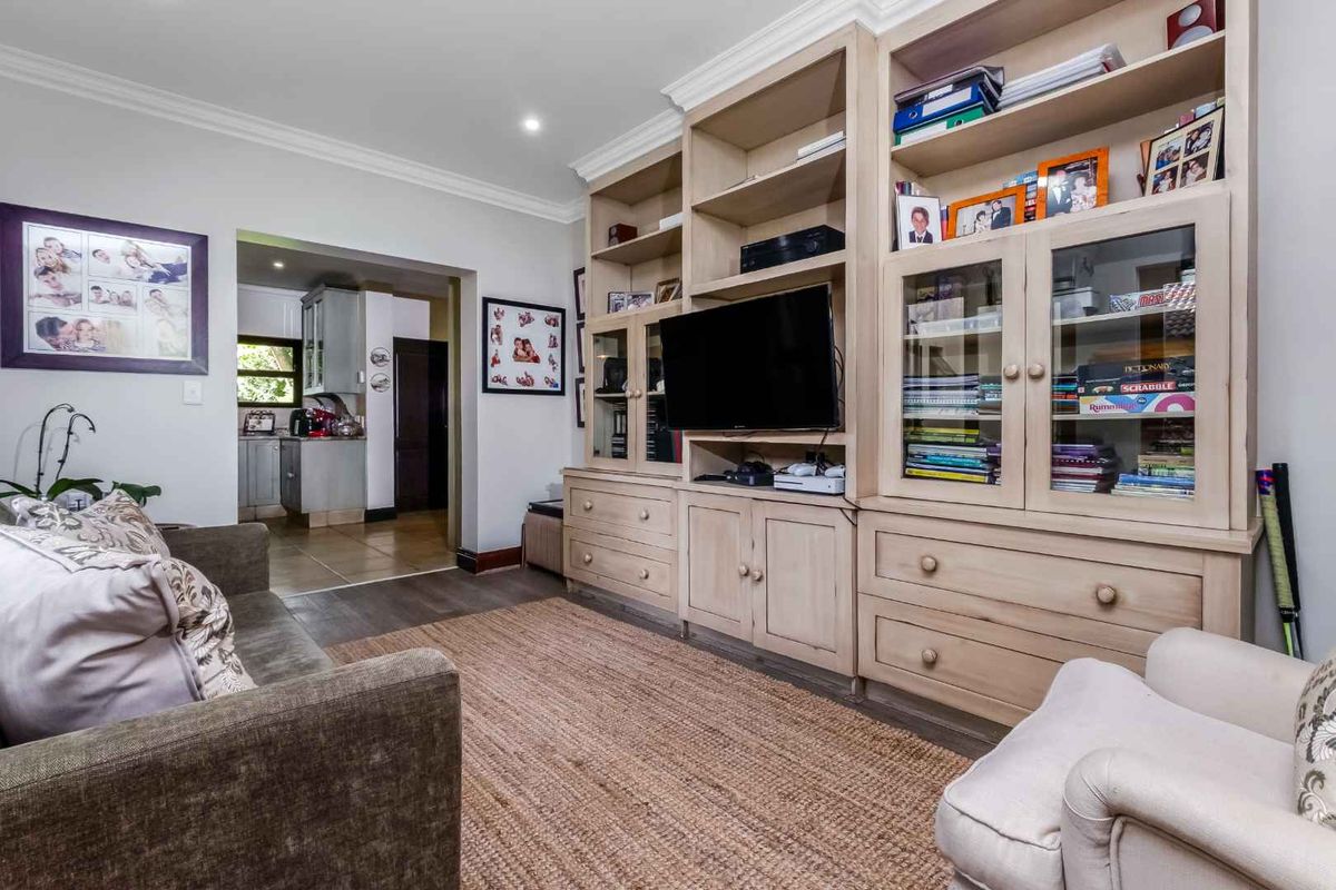 A comfortable living room featuring extensive built-in wooden cabinetry and shelving, with a seamless transition into the adjacent kitchen area.