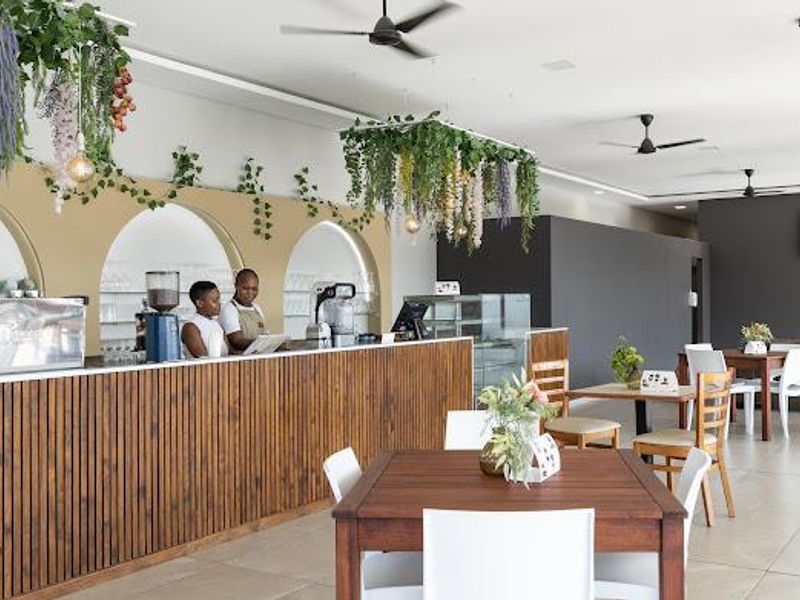 Modern open-plan commercial space featuring a timber slat service counter, decorative arched wall niches, and ceiling fans, suitable for a cafe or hospitality setting.