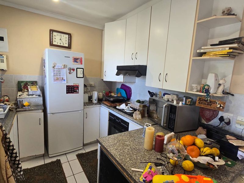 A functional kitchen featuring granite countertops, built-in cabinetry, and an integrated oven, offering a practical layout with potential for modern cosmetic updates.