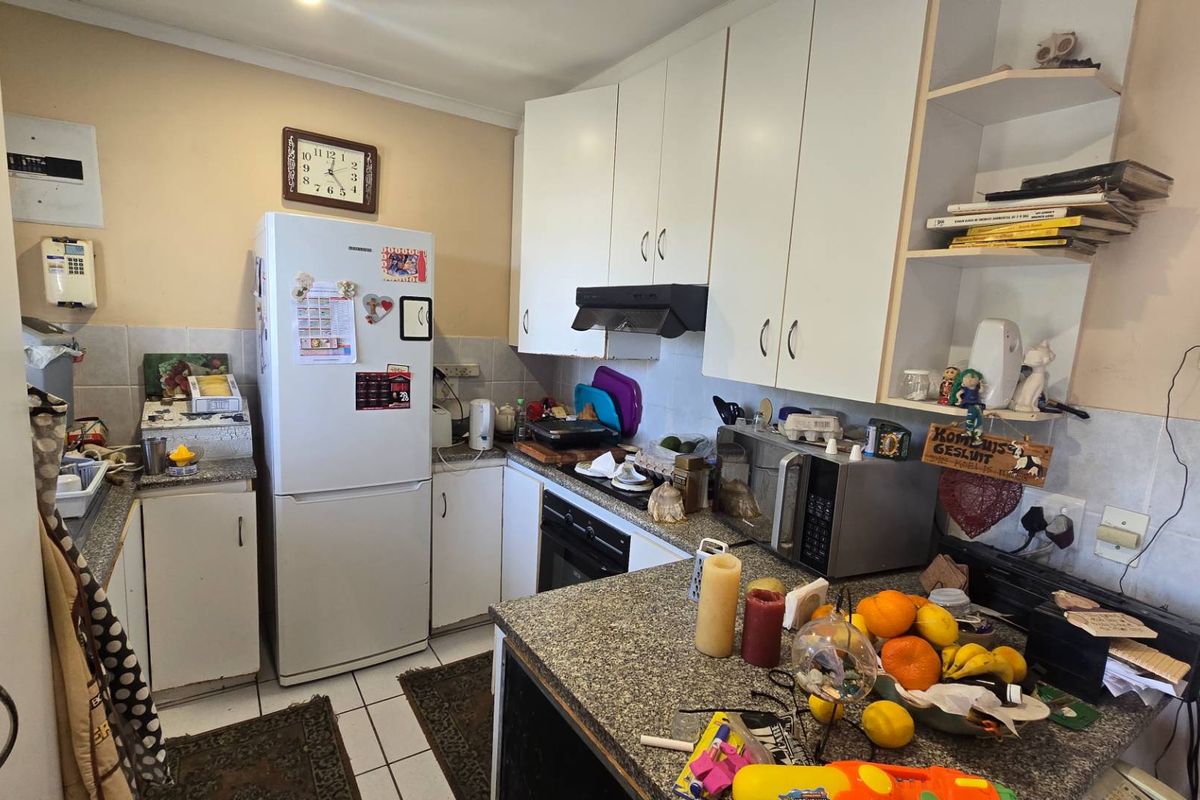 A functional kitchen featuring granite countertops, built-in cabinetry, and an integrated oven, offering a practical layout with potential for modern cosmetic updates.
