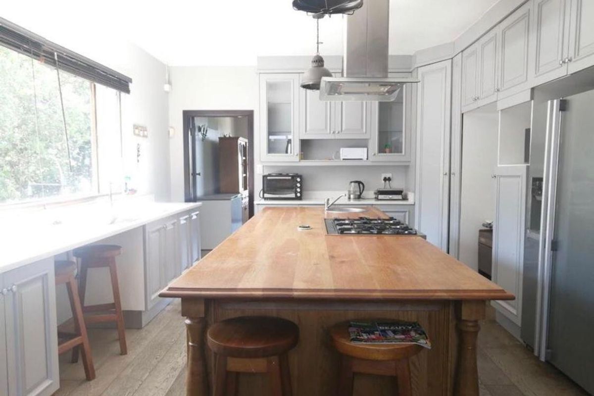 A well-appointed kitchen featuring a large wooden island with a built-in gas hob, ample cabinetry, and modern pendant lighting.